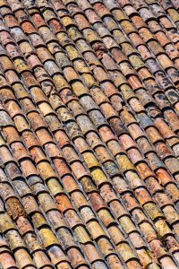 Old roof made of traditional Roman terracotta tiles on an old house in the south of France. Close-up for texture