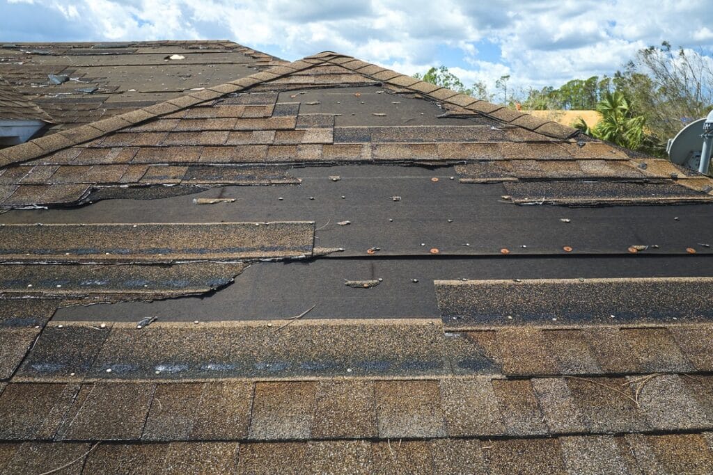 Damaged house roof with missing shingles